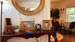 Une pièce avec un grand miroir rond, un bureau avec une lampe, une chaise et une plante.