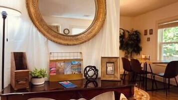 A room with a large round mirror, a desk with a lamp, a chair, and a plant.