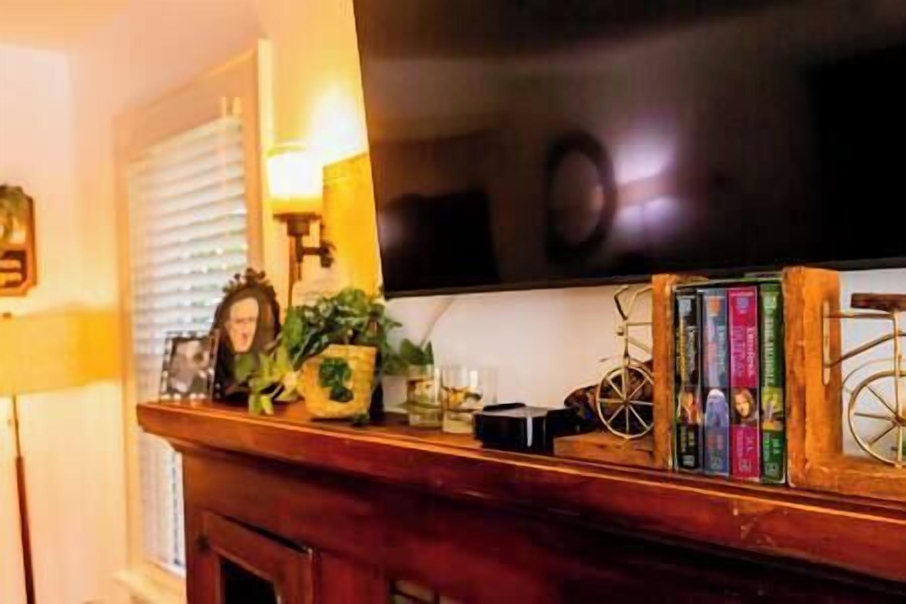Una estantería de madera con libros, una planta pequeña y un adorno.