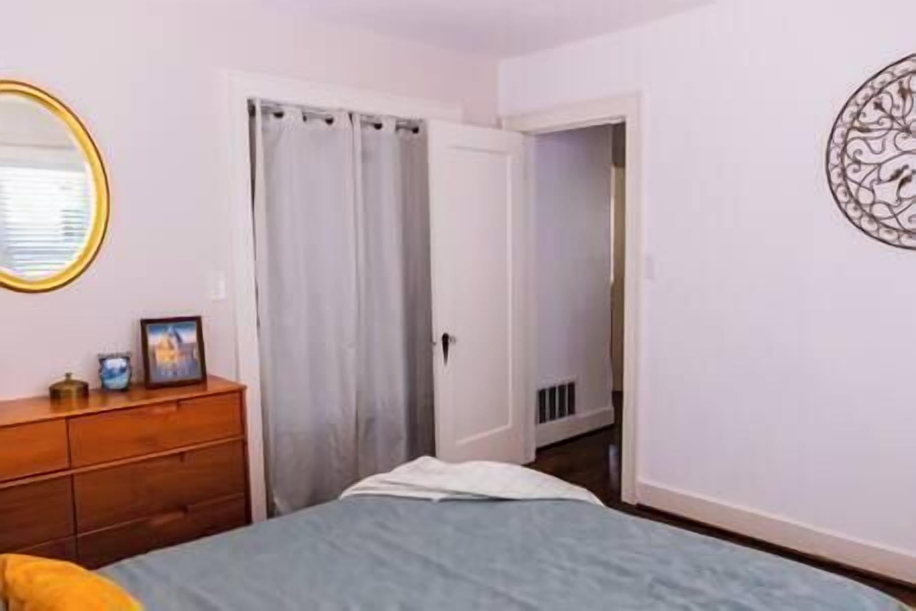Un dormitorio con cama, cómoda, puerta y decoración en la pared.