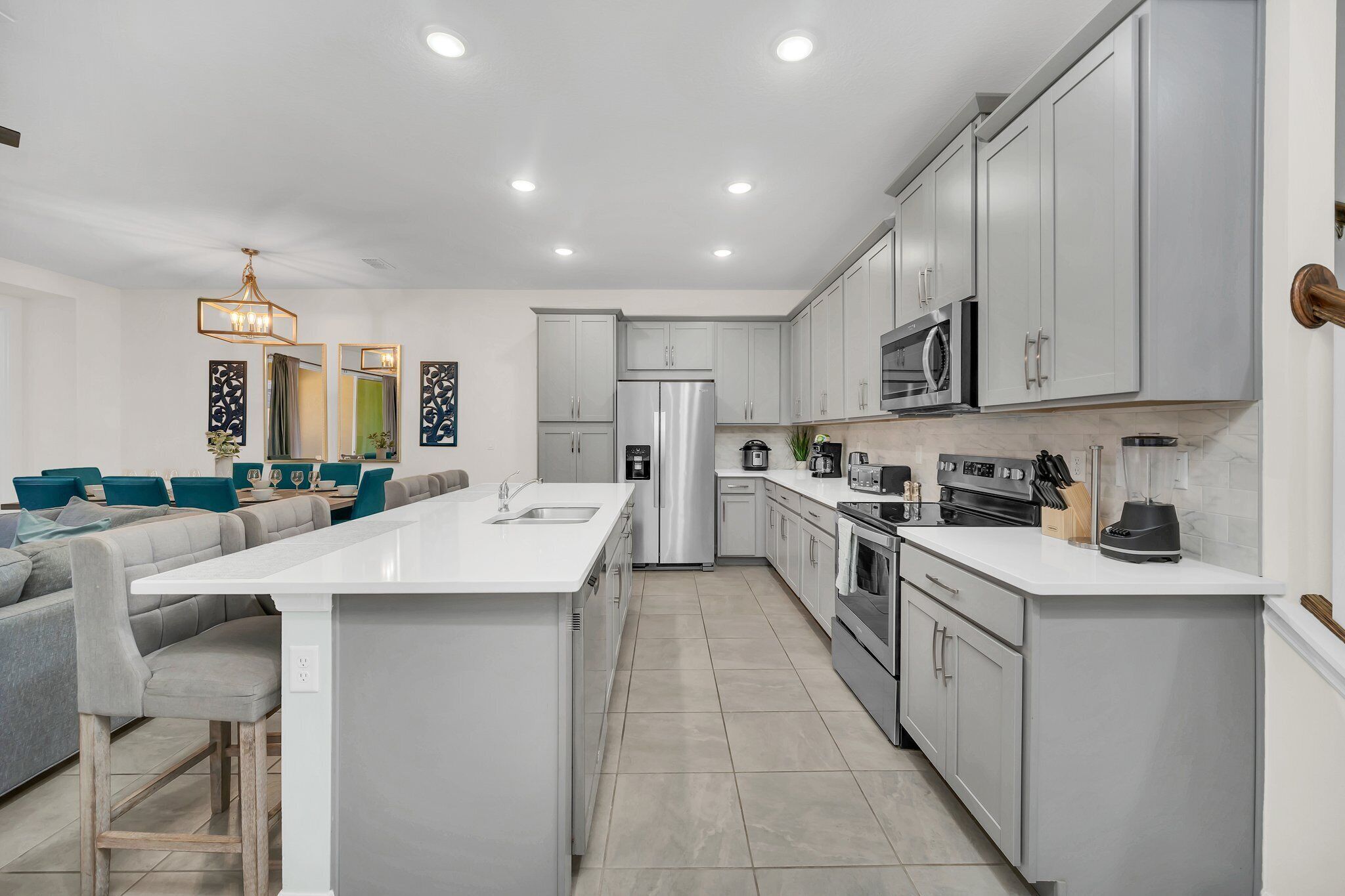 A modern kitchen with a central island, stainless steel appliances, and light grey cabinetry.