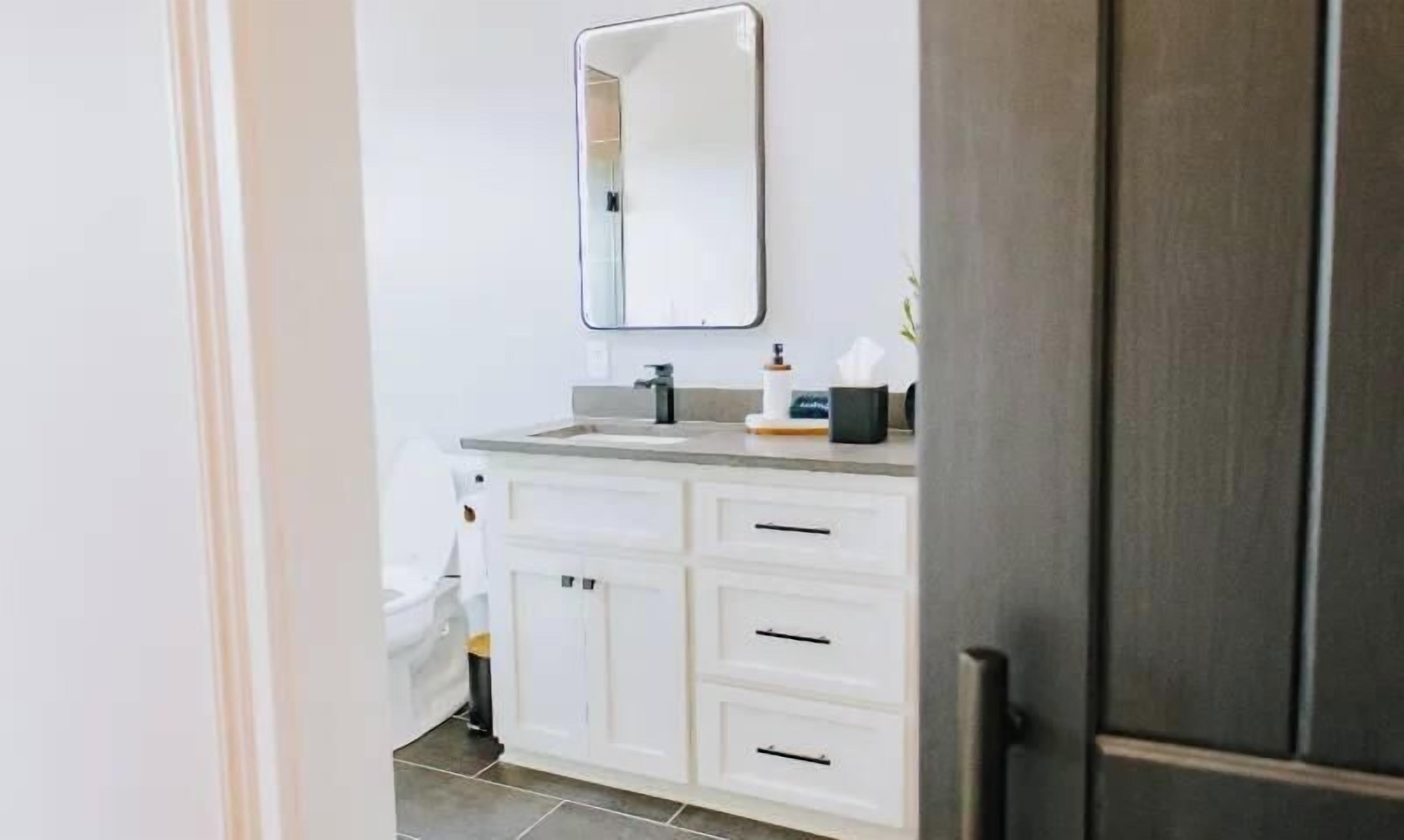 Une salle de bain avec un meuble-lavabo blanc, un miroir et des toilettes.