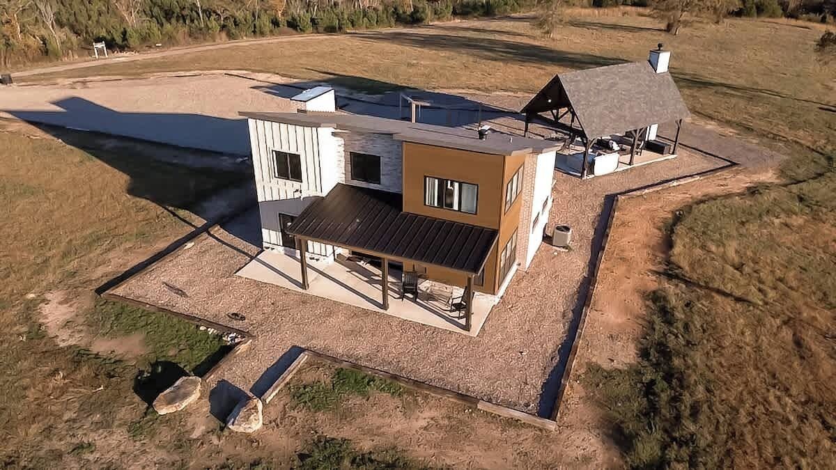 Una casa moderna de dos pisos con un amplio patio y un garaje independiente.