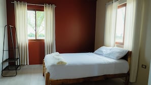 A single bed with white linens in a room with wooden flooring and red walls. - Casa Hacienda Las Palmeras (Patapo)
