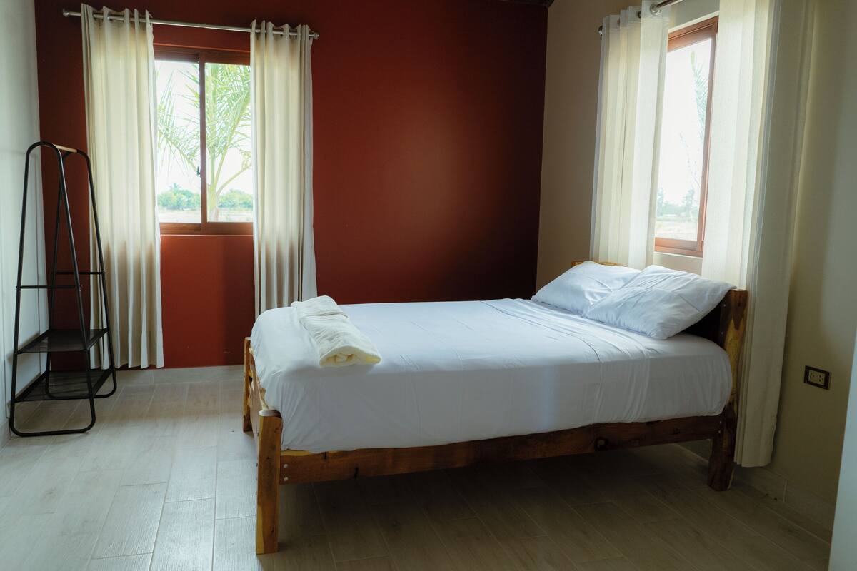 Ein Einzelbett mit weißer Bettwäsche in einem Zimmer mit Holzboden und roten Wänden.