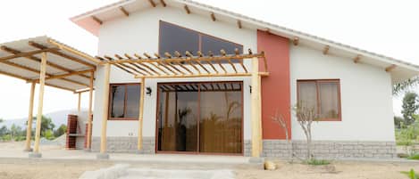 Una casa moderna con un porche cubierto, grandes puertas correderas de vidrio y un cimiento de piedra.