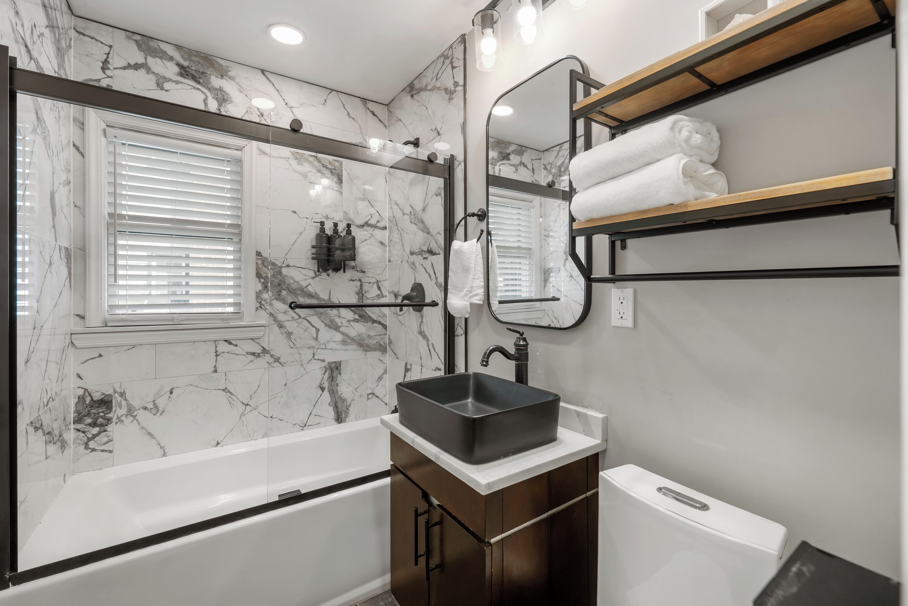 Une salle de bain moderne équipée d’une baignoire, d’un meuble-lavabo avec un évier, d’un miroir et d’un porte-serviettes.