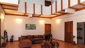 Un vaste espace de vie agrémenté d’un canapé marron, d’une sculpture en bois représentant un éléphant et d’un grand tableau accroché au mur.