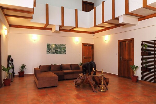 A spacious living area with a brown sofa, a wooden elephant sculpture, and a large painting on the wall. - Johns Solitude (Kunchithanny)