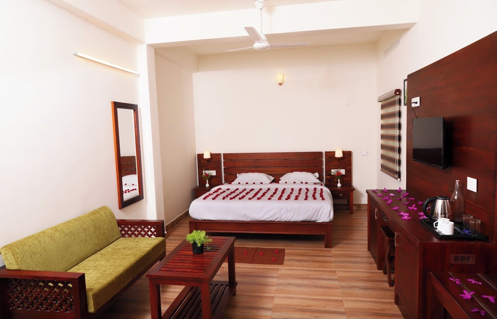 A hotel room with a bed, a sofa, a coffee table, a TV, and a wooden cabinet.