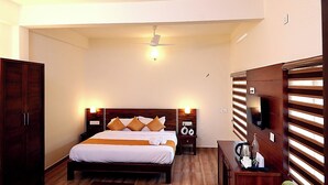 Une chambre à coucher comprenant un lit, une tête de lit en bois, des tables de chevet, un ventilateur de plafond et une armoire.