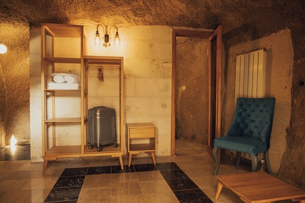 A cozy room with a wooden cabinet, a blue chair, and a suitcase.