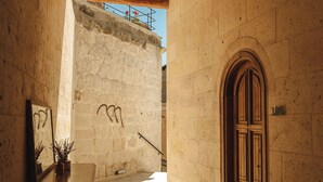 A corridor with a wooden ceiling, a stone wall, and a wooden door with a number plaque. - Juno Cappadocia (Nevsehir)