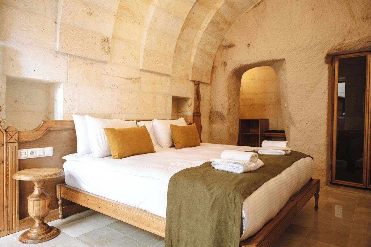 Un dormitorio espacioso con una cama grande, cabecero de madera y una pared de piedra.