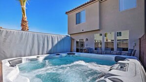 A hot tub in a backyard with a house in the background.