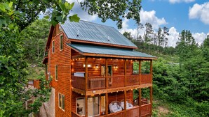 Eine zweistöckige Blockhütte mit Balkon, umgeben von dichtem Wald.