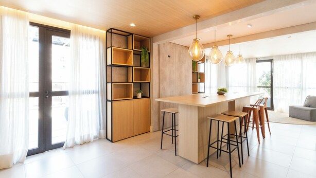 Una cocina moderna con una isla central, taburetes de bar e iluminación colgante.