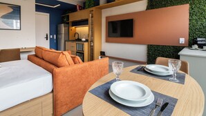 Una habitación de hotel moderna con zona de comedor, sofá, cama y cocina.