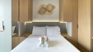 Una cama bien hecha con sábanas blancas, cabecera y un adorno en la pared.