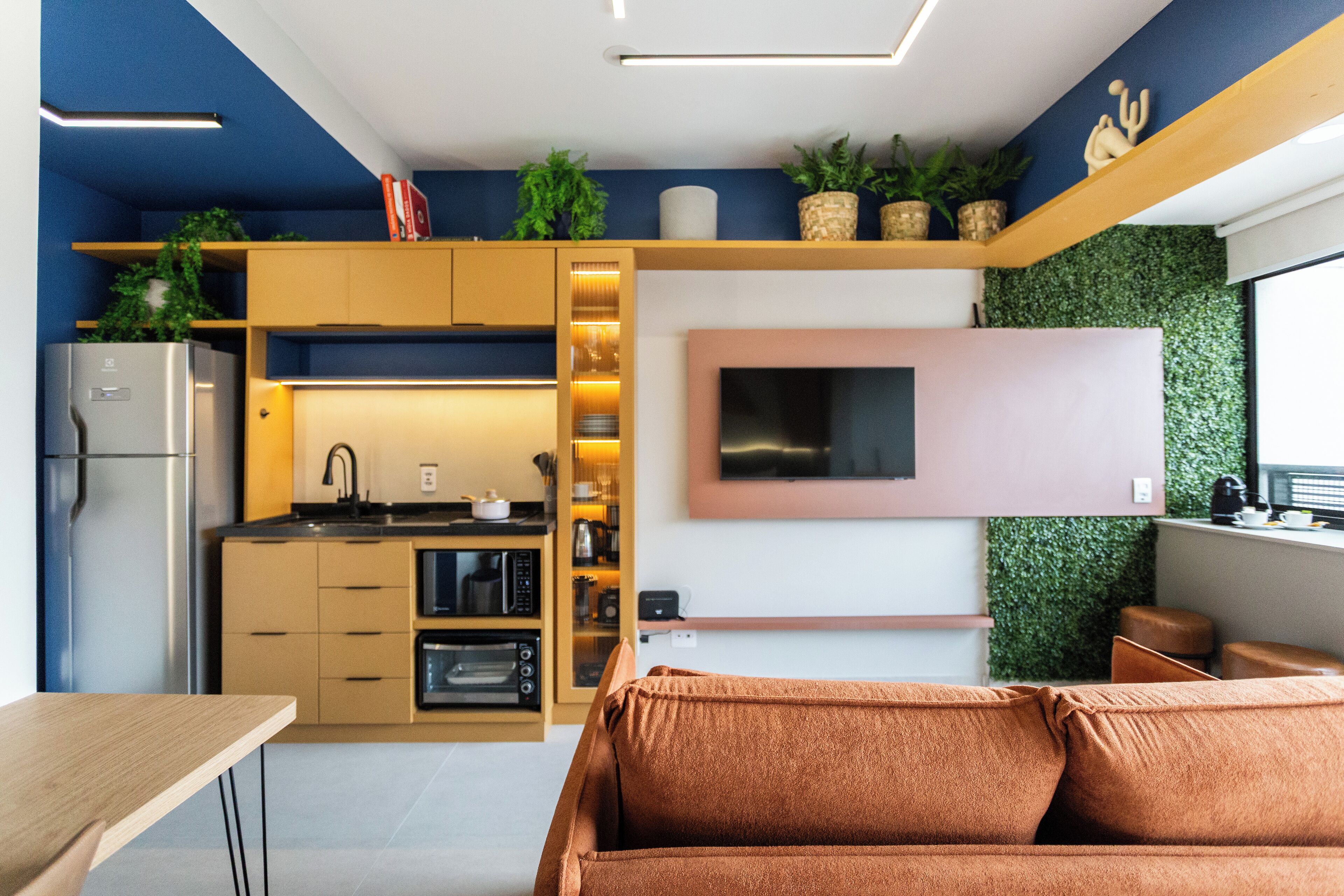 Une cuisine moderne dotée d’appareils électroménagers intégrés, d’un téléviseur à écran plat et d’un mur végétal.