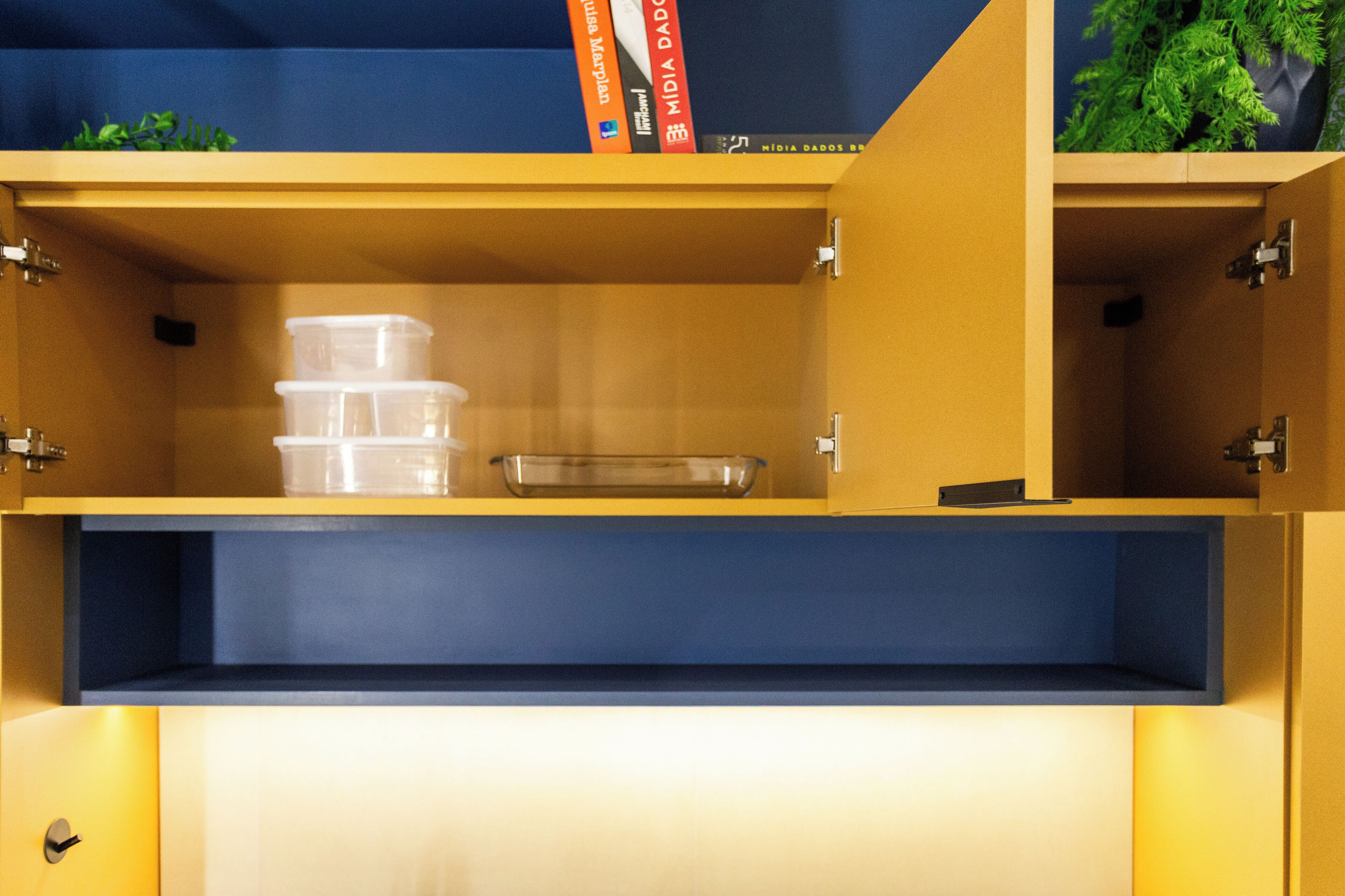 Ein Stauraumschrank mit mehreren Fächern, darunter durchsichtige Kunststoffbehälter und eine Glasplatte.
