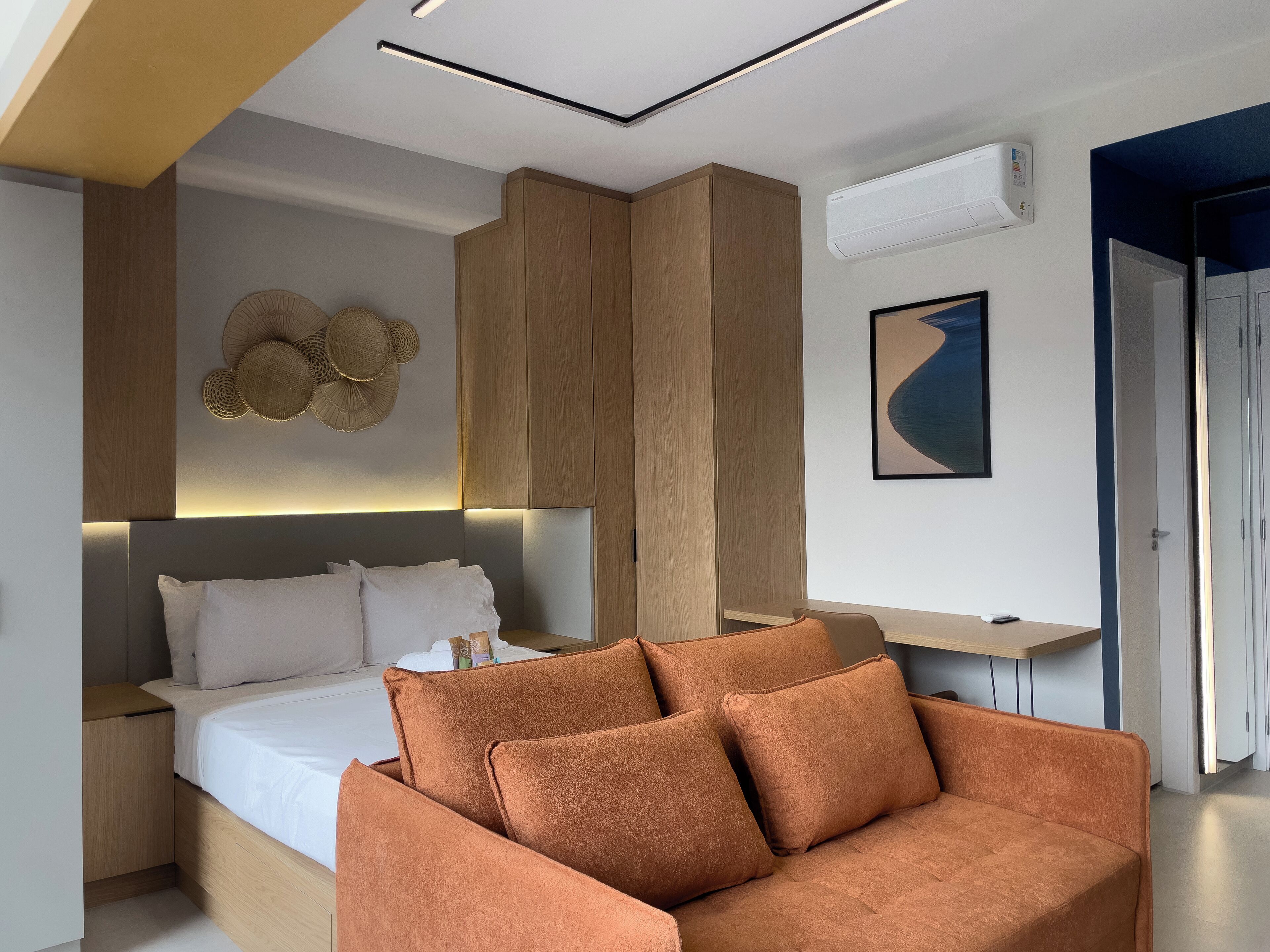 Ein modernes Schlafzimmer mit einem Bett, einem Holzschrank, einer Wand-Klimaanlage und einem gerahmten Kunstwerk.