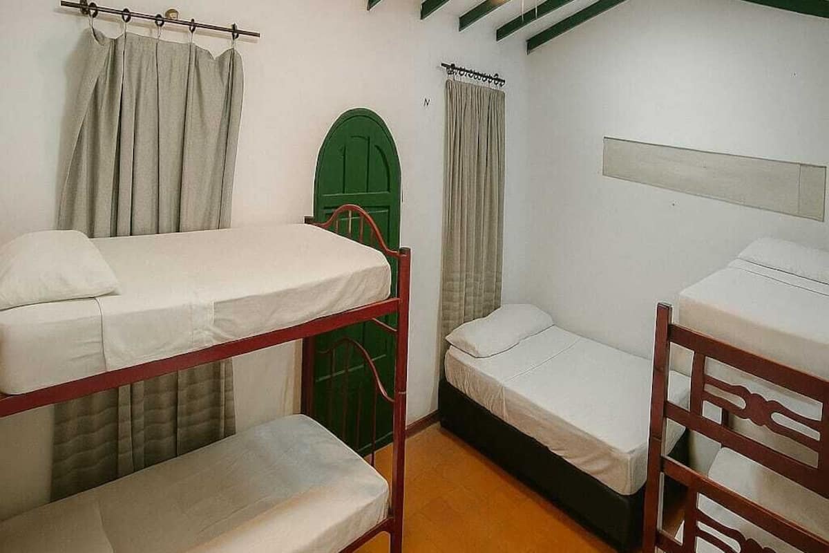 Quarto de dormitório com beliches, ventilador de teto e janela com cortinas.