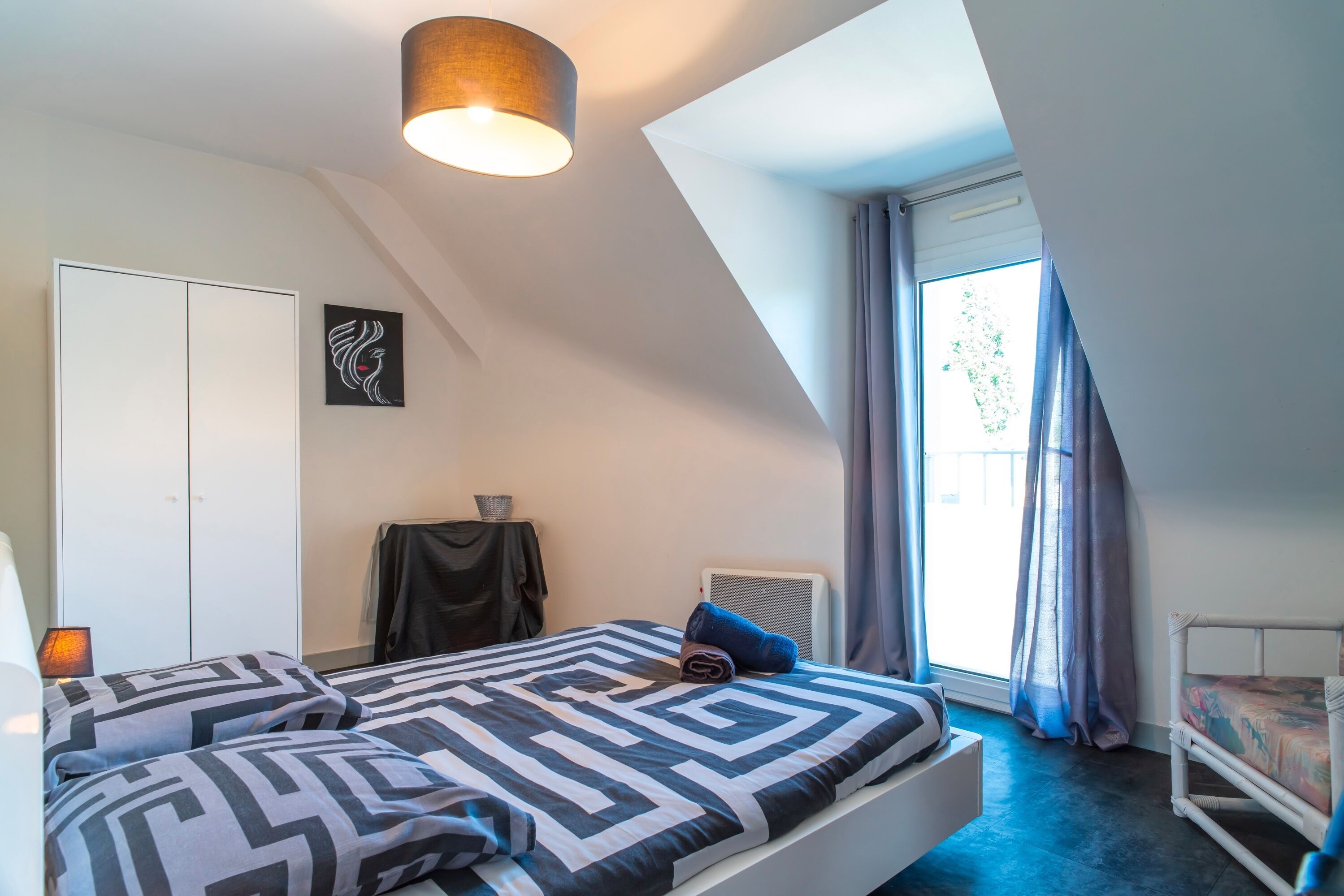 A bedroom with a bed, a wardrobe, a desk, and a window with curtains.