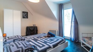 A bedroom with a bed, a wardrobe, a desk, and a window with curtains. - Le Narbon - maison proche de la plage (Erdeven)