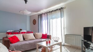 A living room with a sofa, coffee table, and a TV stand. - Le Narbon - maison proche de la plage (Erdeven)