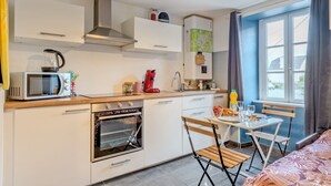 A modern kitchen with white cabinets, a microwave, a red coffee maker, and a dining area with a table and chairs.