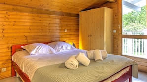 Una habitación de cabaña de madera con cama, almohadas y toallas.