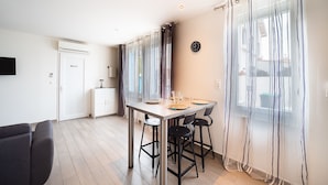 A modern kitchen with a dining table set for four, a refrigerator, and a clock on the wall.