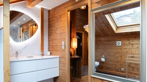 Un baño de cabaña de madera con tragaluz, un tocador blanco y un espejo.