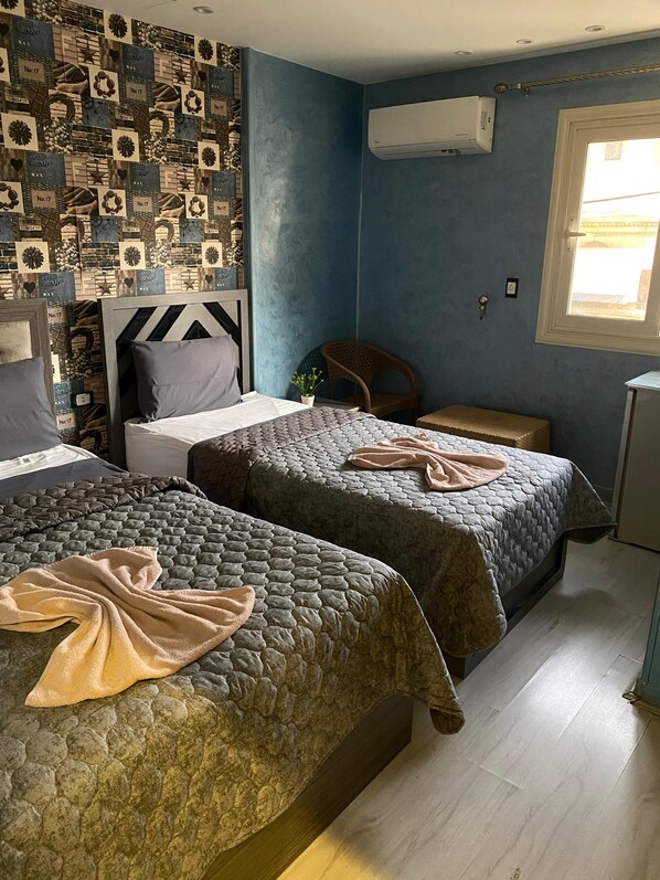 Ein Zimmer mit zwei Betten, einem Fenster und einer Wand, die mit Vintage-Fliesen verziert ist.