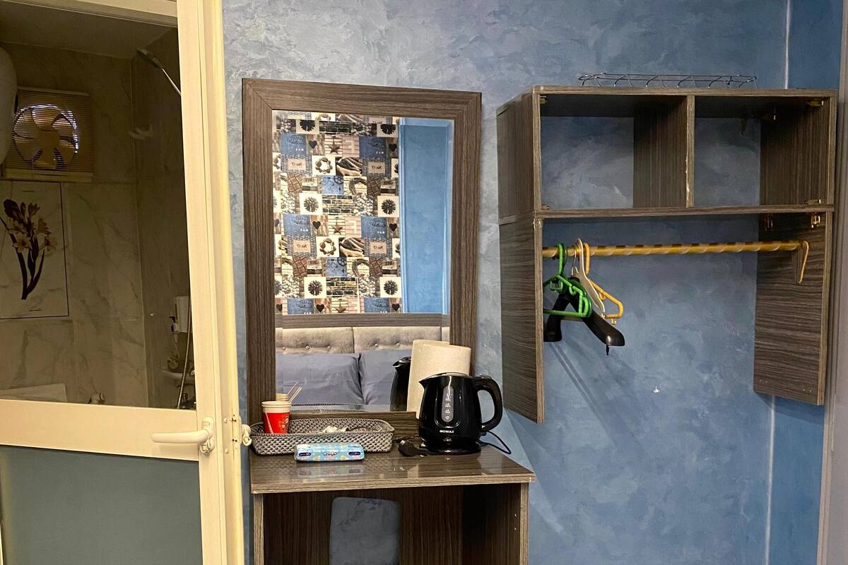 Ein kleines Zimmer mit integriertem Schreibtisch, einer Kaffeemaschine und einem Spiegel.