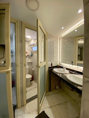 A modern bathroom with two sinks, a toilet, and a shower. - Sunset Hostel (Cairo)