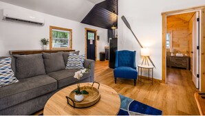 A modern living room with a grey sofa, a blue armchair, and a wooden coffee table with a plant. - Lakeview Deck| 10 mi from TC | Sauna | Hot Tub (Traverse City)