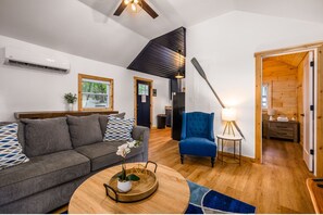Un salon moderne avec un canapé gris, un fauteuil bleu et une table basse en bois agrémentée d’une plante.