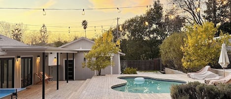 Un patio trasero con un jacuzzi, una piscina y un área de patio techada.