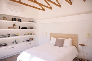 A bedroom with a bed, a white wardrobe, and a shelf with books and decorative items. - Designer Sonoma Getaway with Pool, Hot Tub & Bocce (Sonoma)