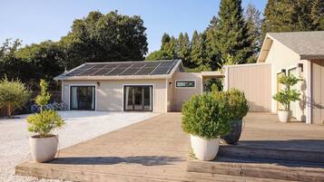 A modern house with a solar panel roof, a covered patio, and potted plants.