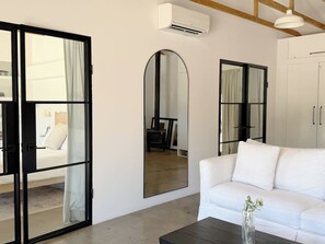 Una sala de estar moderna con un sofá blanco, una mesa de centro y un espejo grande.