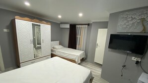 Ein Hotelzimmer mit zwei Betten, einem Kleiderschrank, einem Fernseher und einer Klimaanlage.