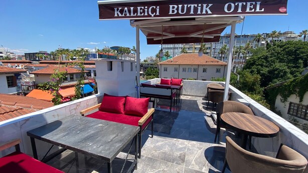 Eine Dachterrasse des Kaleici Butik Otel mit überdachter Sitzecke, Tischen und Stühlen.