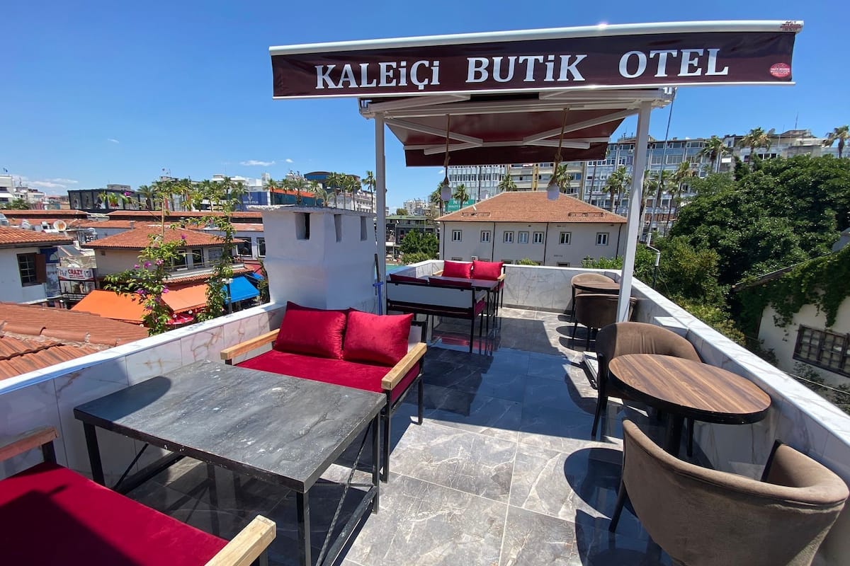 A rooftop terrace of Kaleici Butik Otel with a covered seating area, tables, and chairs.