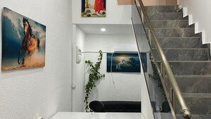 Eine Treppe mit Marmorstufen und einem Metallgeländer, gesäumt von weißen Wänden und Kunstwerken.