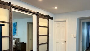 Una habitación con piso de madera, una puerta corredera y una puerta blanca.