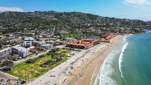Un paisaje urbano costero con playa, edificios residenciales y un fondo montañoso.