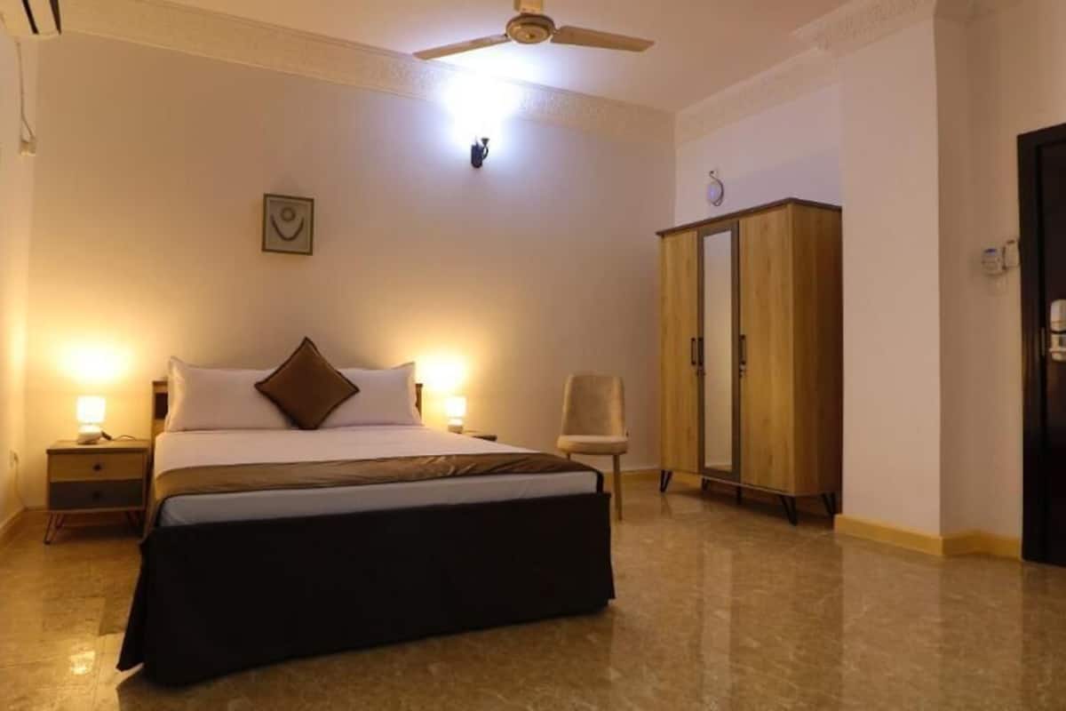 A bedroom with a bed, nightstand, wardrobe, and a ceiling fan.